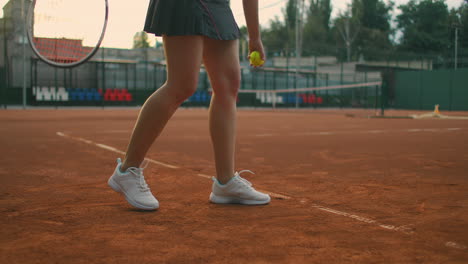 For-tennis-training-a-girl-stands-on-the-central-service-line.-Bangs-the-ball-on-the-court.-Serve.-the-camera-moves-from-the-ground-to-medium-close-up